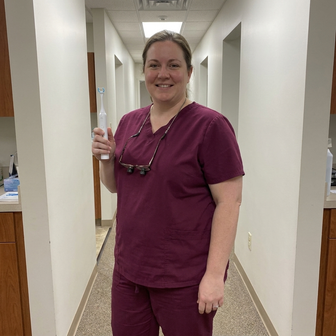 Dental hygienist holding Essoon in a practice hallway