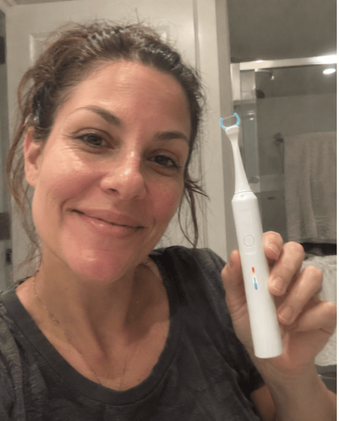 Claire B. holding the Essoon flosser in her bathroom